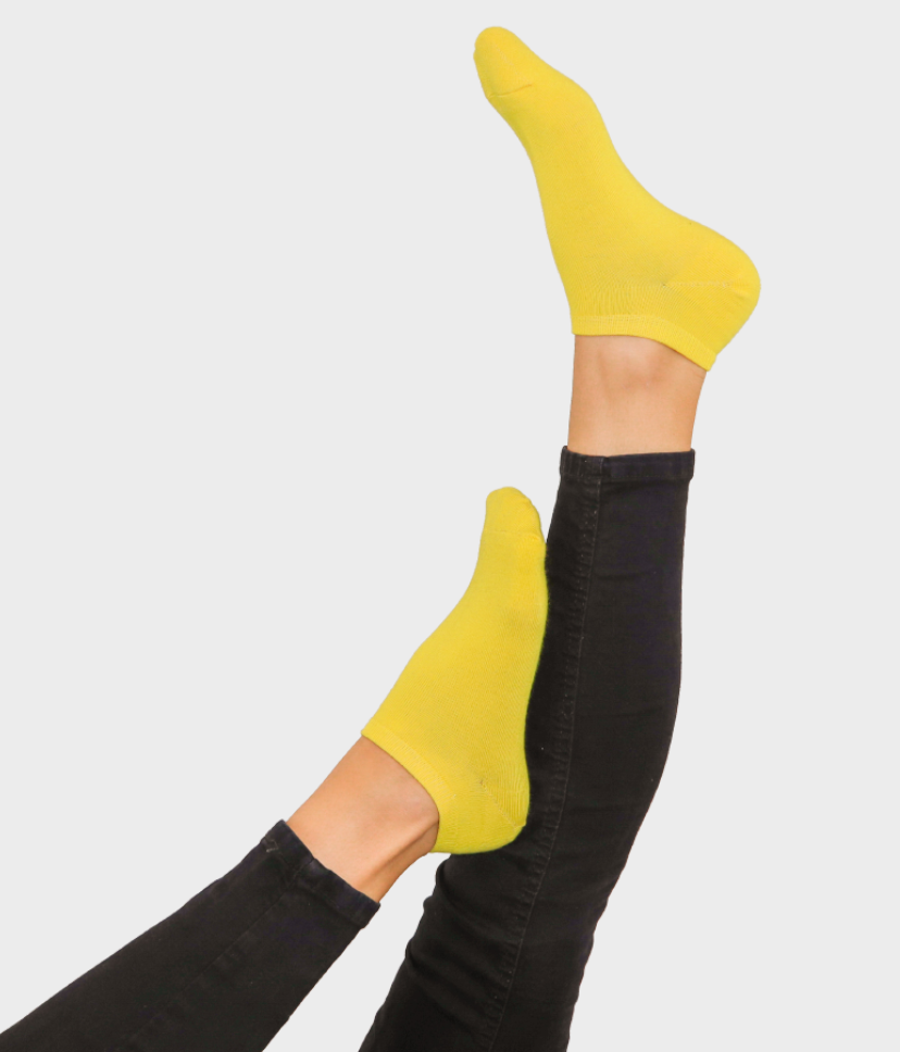 Felfelé álló lábakon egyszínű, vibráló sárga Goisocks bokazokni.