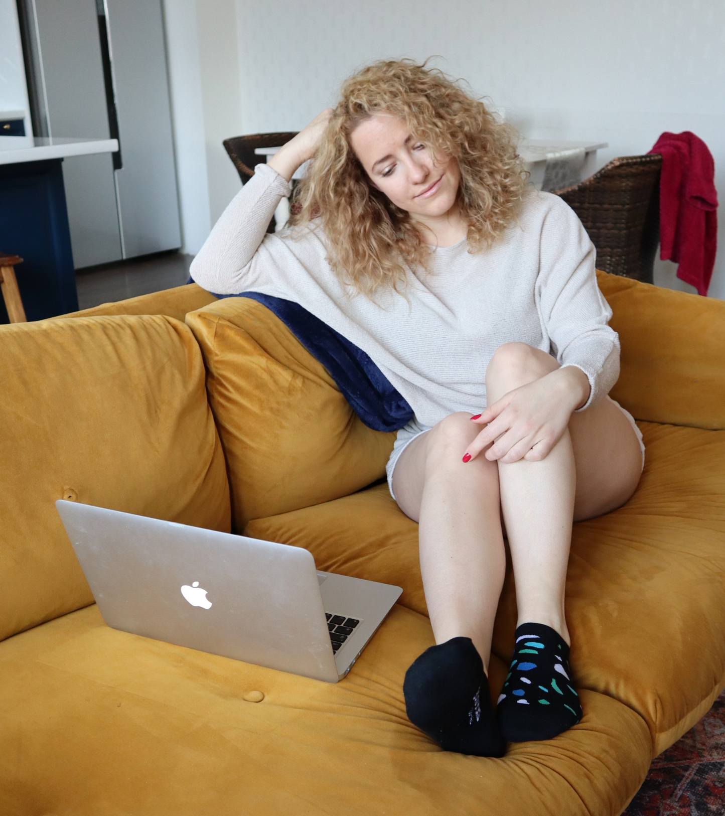 Vidám lány laptoppal ül a kanapén és Goisocks Jól bevált Fekete kavicsos zoknit visel.